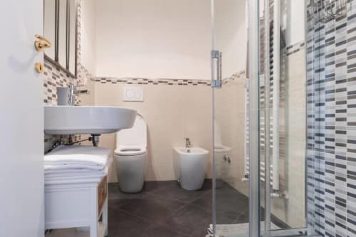 Bagno moderno nell'appartamento Proprietà Clara ad Assisi con doccia in piastrelle grigie, lavabo rotondo e bidet