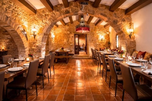Capilla de piedra con arcos y mesas preparadas bajo vigas de madera.
