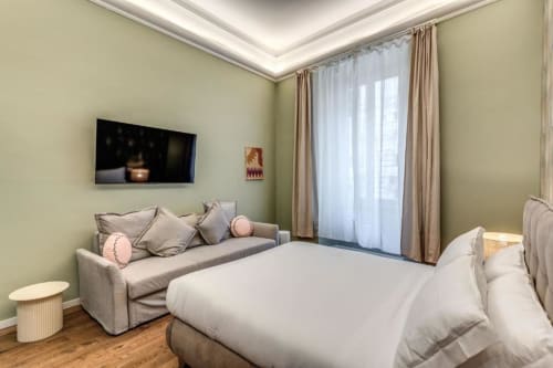 Camera moderna con vista sulla città, divano grigio, letto bianco e smart TV nell'appartamento The Great Chill, Roma