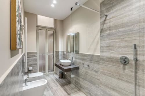 Bagno moderno in appartamento romano con piastrelle grigie, doccia walk-in, doppi lavabi e finiture contemporanee