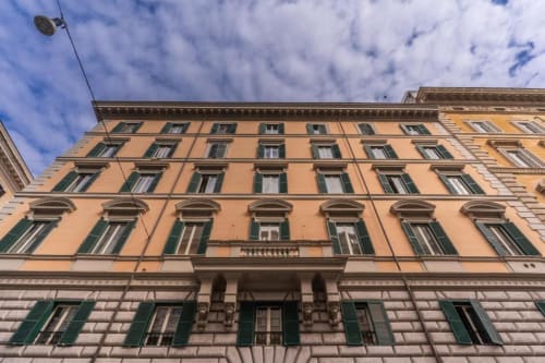 Facciata classica di palazzo romano con muri arancioni e persiane verdi nel centro di Roma