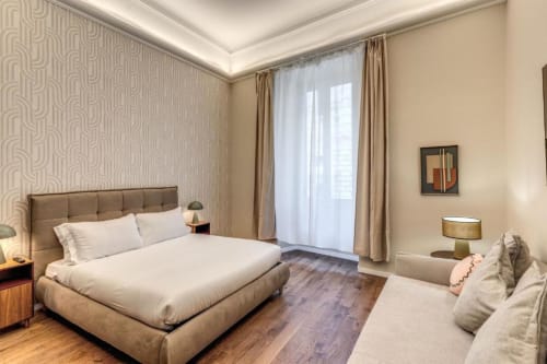 Camera da letto moderna nell'appartamento Downtown Roma con letto color tortora, balcone con vista sulla città e arredi contemporanei