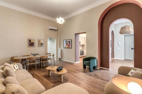 Moderno soggiorno di appartamento a Roma con divano beige, tavolo in legno e arco in terracotta all'ingresso