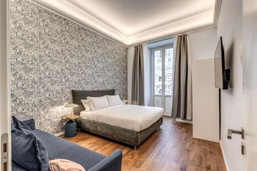 Camera da letto moderna a Roma con carta da parati geometrica, letto matrimoniale, balcone con vista sulla città e arredamento contemporaneo