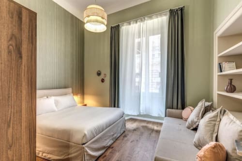 Camera moderna dell'appartamento Downtown Srl a Roma con letto queen size, pareti verde, armadio in legno, balcone con vista sulla città