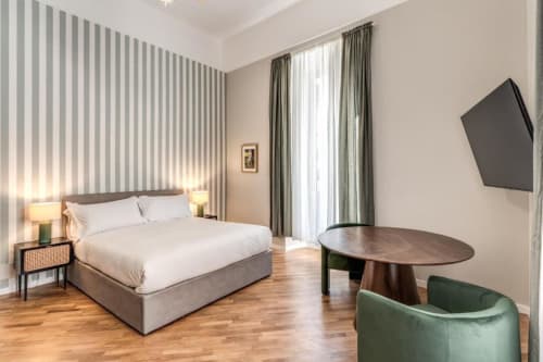 Camera da letto moderna dell'appartamento Downtown Roma con parete a righe, letto queen, pavimenti in legno, TV e accenti verdi