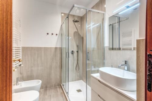 Bagno moderno in appartamento a Roma con doccia in vetro, lavabo bianco, WC e scaldasalviette riscaldato