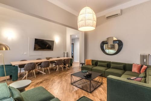 Zona living moderna con divano verde, tavolo da pranzo e lampadario a sospensione nel centro di Roma