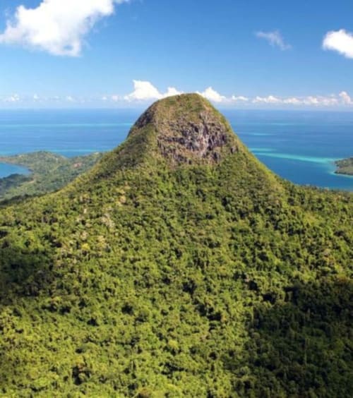 Sommet de montagne volcanique verdoyant surplombant l'océan turquoise près de Mamoudzou, Mayotte