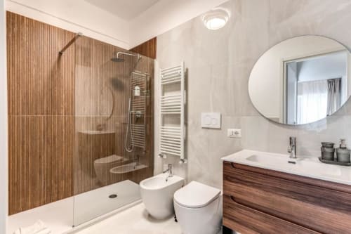 Bagno moderno nell'appartamento The Cloud presso Downtown Srl Roma con parete in legno, doccia in vetro, sanitari bianchi e dettagli tondi