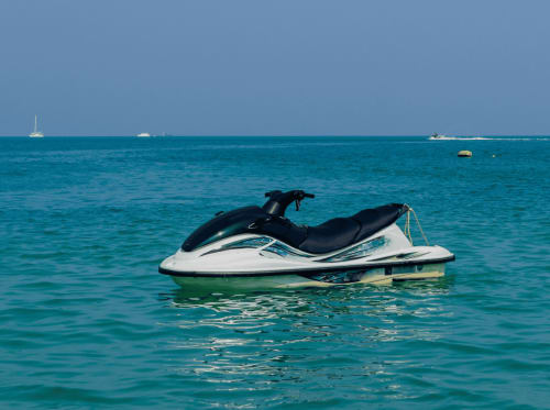 Jet ski noir et blanc amarré dans les eaux turquoise près de Kaz Kafe, Mamoudzou, avec des voiliers à l'horizon