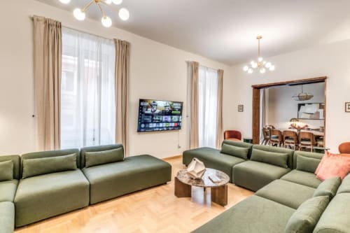 Moderno soggiorno di appartamento a Roma con divani modulari verdi, pavimenti in legno e TV a schermo piatto