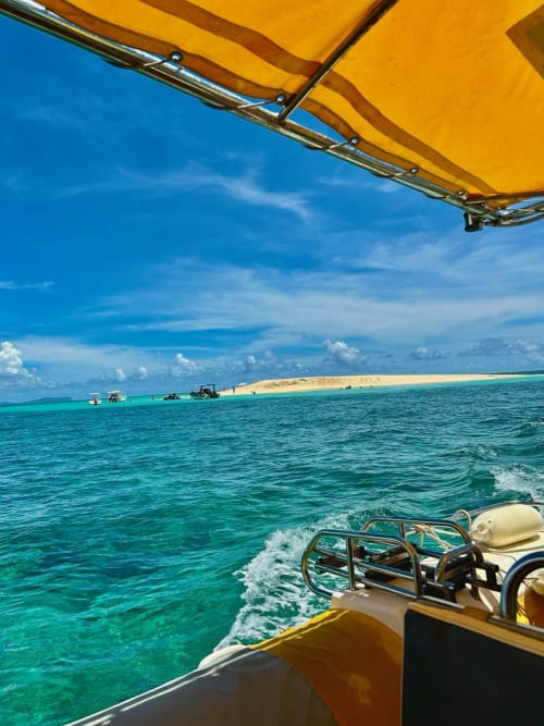 Bateau jaune avec auvent surplombant un lagon turquoise et une île de sable fin, Mamoudzou Mayotte