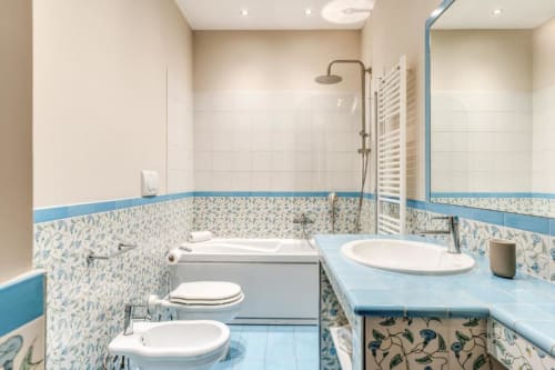Bagno moderno blu e bianco con vasca, bidet, lavabo e doccia walk-in nell'appartamento Downtown Nobu a Roma