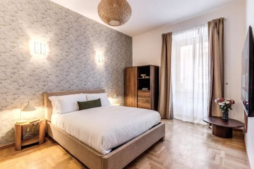 Camera da letto moderna nell'appartamento Nobu del Downtown di Roma, con letto in legno, biancheria bianca, carta da parati decorativa e pavimenti in legno