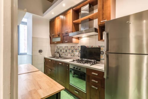 Cucina moderna nell'appartamento Downtown Nobu di Roma con mobili in legno, elettrodomestici in acciaio inox e piano cottura a gas