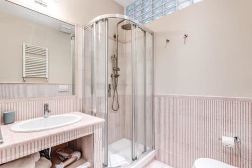 Bagno moderno in appartamento Downtown Nobu a Roma con rivestimento in piastrelle rosa, doccia angolare, lavabo bianco e riscaldato