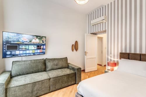 Monolocale moderno a Roma con divano verde, TV a schermo piatto, parquet e accesso alla camera da letto presso Downtown Nobu