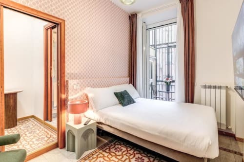 Camera da letto di lusso nel centro di Roma con letto matrimoniale, balcone panoramico, carta da parati decorativa e arredi moderni