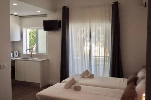 Estúdio com varanda na Hospedaria Buganvília Alvor com camas, kitchenete, TV e vista para o jardim em Alvor, Portugal