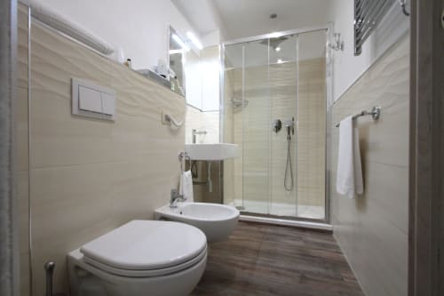 Modern bathroom at Il Viottolo B&B in Roccaraso with white fixtures, rainfall shower, and wood-look flooring