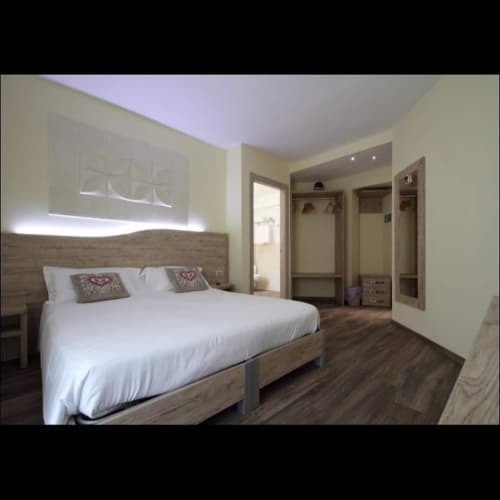 Camera moderna all'Il Viottolo di Roccaraso con letto queen, testata in legno, arte murale illuminata, guardaroba e arredamento contemporaneo