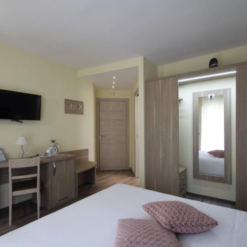 Modern junior suite at Il Viottolo in Roccaraso with bed, desk, TV, and mirrored wardrobe