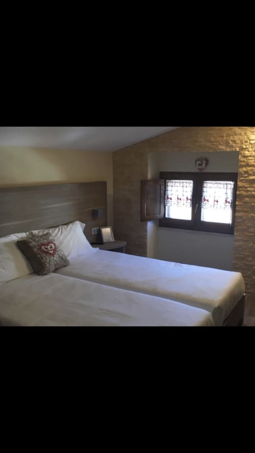 Camera moderna con letto biancheria bianca, testata in legno e vista sul paesaggio dalle doppie porte dell'Il Viottolo B&B a Roccaraso