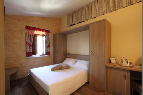 Camera moderna a Il Viottolo a Roccaraso con letto in legno integrato, pareti gialle e finestra con tende rosse