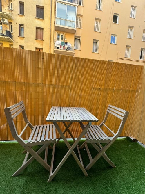 Spacieux espace de salle à manger extérieure à Bastia avec table en bois, chaises et terrasse en gazon artificiel.