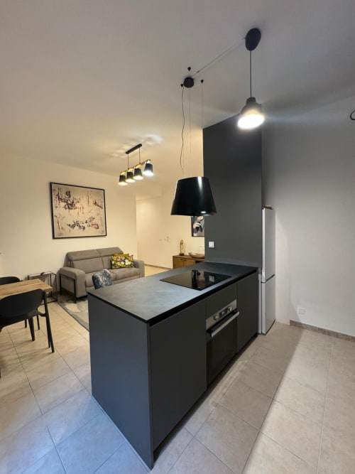 Cuisine moderne avec îlot dans un spacieux appartement à Bastia Altezza, ouvrant sur le salon avec canapé