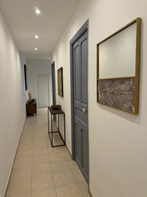 Couloir moderne de l'appartement à Bastia avec portes grises, œuvres encadrées, meubles en bois et carrelage