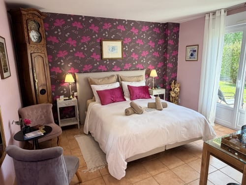 Chambre double élégante aux Vieilles Digues avec papier peint floral magenta, linge blanc et vue sur le jardin à Beauvoir