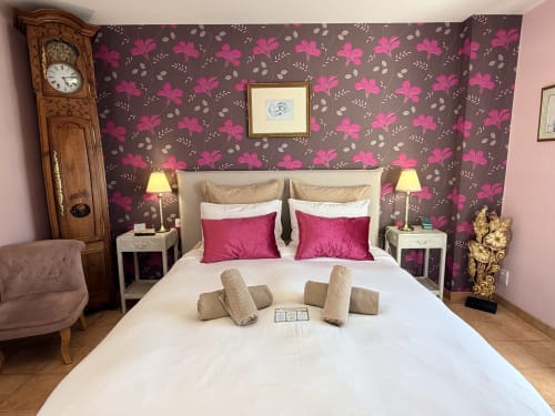 Chambre double élégante à Les Vieilles Digues avec papier peint fleuri, oreillers roses et vue sur le jardin à Beauvoir