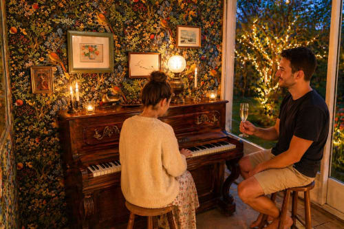 Couple enjoys piano music in elegant room at La Villa Malzy, Vetheuil with festive lights and floral wallpaper