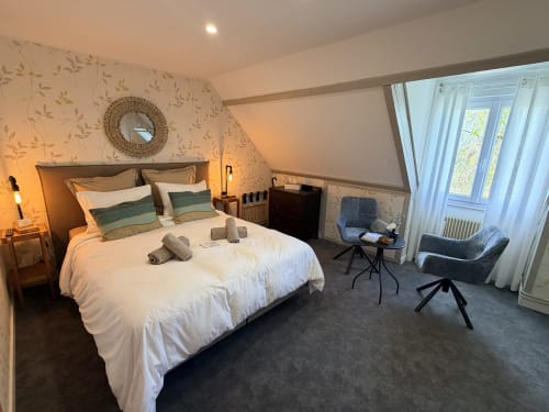Spacieuse chambre double aux Vieilles Digues avec vue sur le jardin, literie blanche, oreillers rayés et coin détente