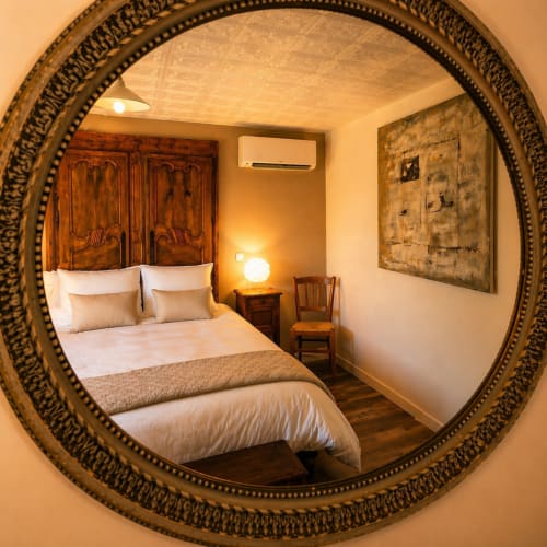 Elegant bedroom at La Villa Malzy in Vetheuil with ornate round mirror frame, wooden headboard, and warm ambient lighting