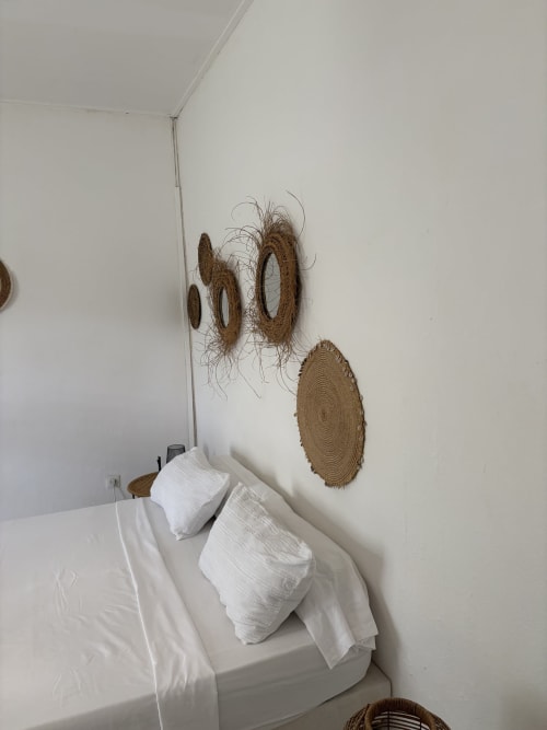 Lit blanc avec serviettes et décoration murale tissée dans la chambre La Paillotte du Kaz Kafe, Mamoudzou
