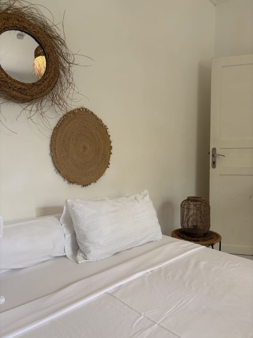 Chambre minimaliste à la Kaz Kafe avec literie blanche, décor mural tissé et porte donnant sur le jardin à Mamoudzou