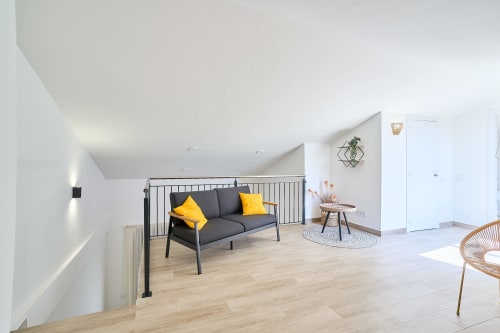 Sala moderna del apartamento Tr3sor 31 en Calella con sofá gris, cojines amarillos y decoración minimalista