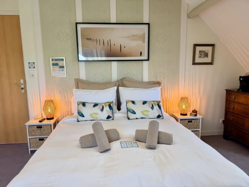 Chambre triple lumineuse aux Vieilles Digues B&B à Beauvoir avec literie blanche, coussins décoratifs et vue sur jardin