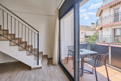 Escalera moderna en apartamento Tr3sor 31, Calella, con acceso a balcón y vistas a la ciudad