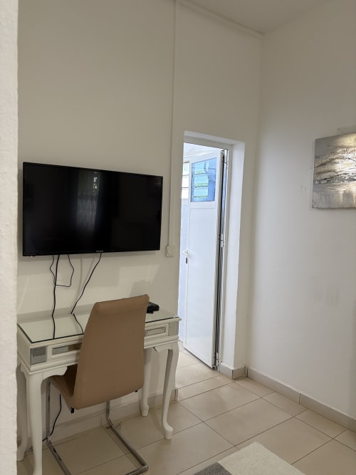 Chambre Zen Bambou au Kaz Kafe avec TV écran plat, bureau, fauteuil beige et vue jardin à Mamoudzou