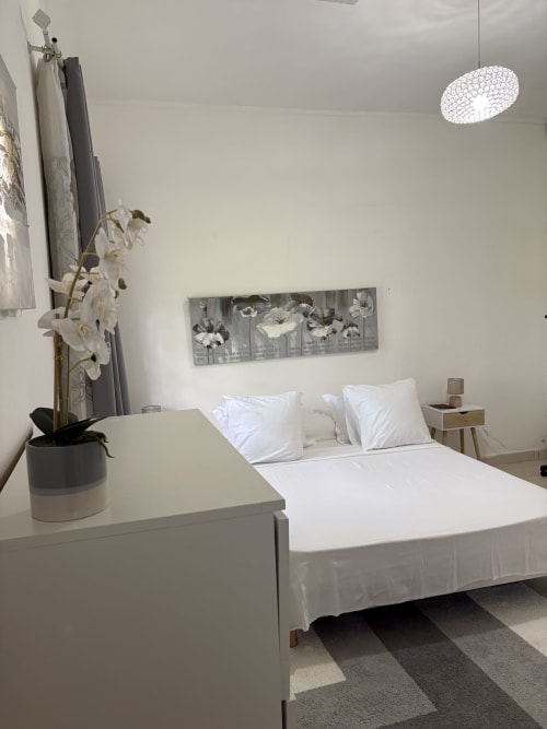 Chambre Zen Bambou au Kaz Kafe BnB de Mamoudzou avec lit blanc, décor minimaliste, orchidée blanche et luminaire moderne
