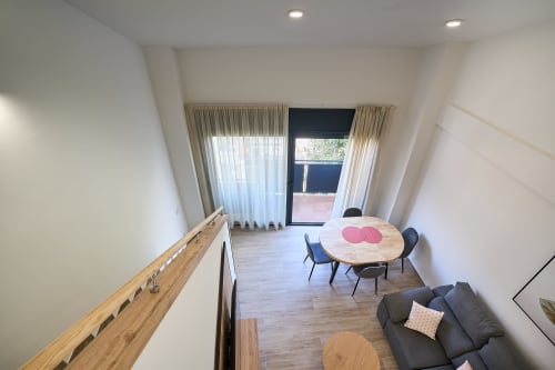 Tr3sor 32 Delux Duplex en Calella con salón abierto, mesa redonda, sofá y acceso a balcón