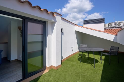 Terraza dúplex de Tr3sor Homes en Calella con mobiliario, césped artificial y arquitectura blanca moderna
