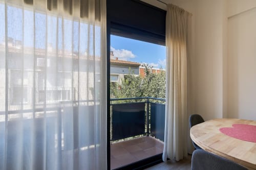 Dormitorio luminoso con vistas a balcón en apartamento Tr3sor Homes Calella, cortinas translúcidas y mobiliario moderno