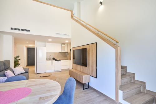 Duplex de lujo Tr3sor Homes en Calella con salón abierto, cocina, TV y escalera