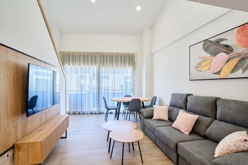 Elegante sala de estar en Tr3sor 32 Delux Duplex, Calella, con sofá gris, comedor y acceso a balcón