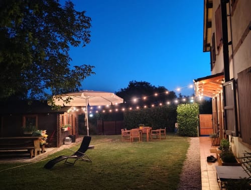 Terrazza del giardino illuminata la sera presso B&B Monte Adone, Monzuno, con posti a sedere, ombrelloni e luci sospese